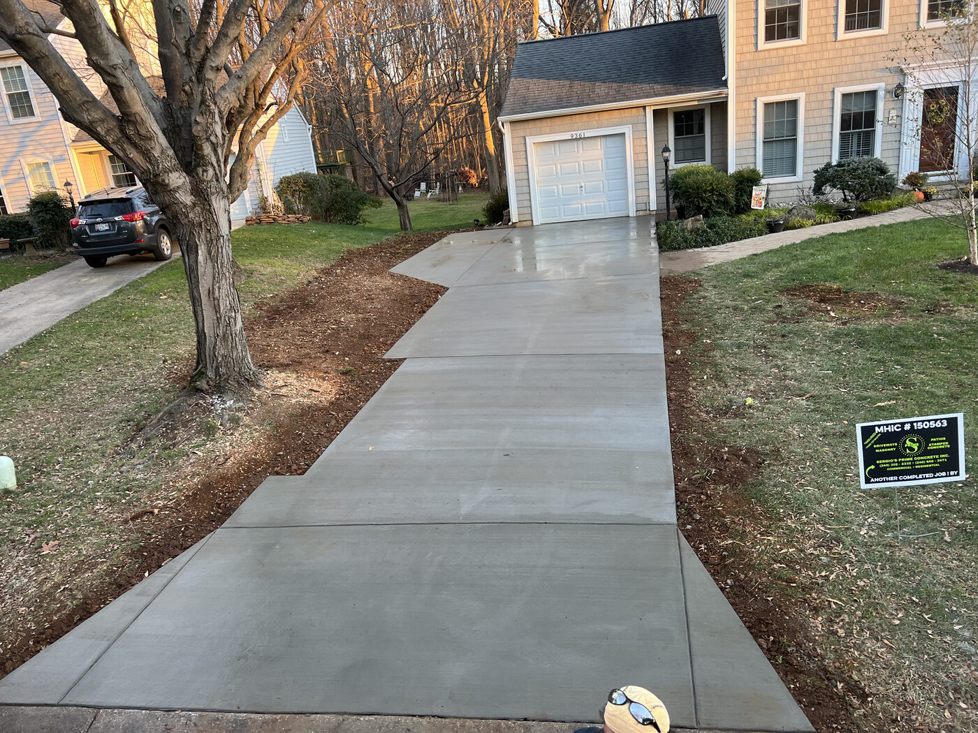 Angular concrete driveway and sidewalk leading to a garage