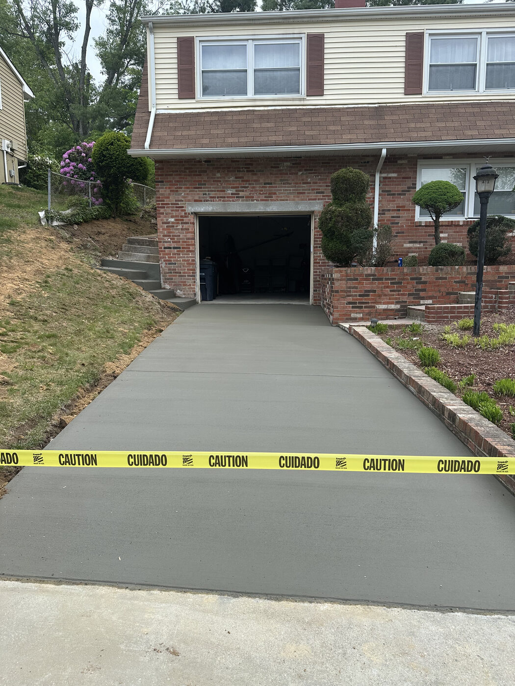 Fresh concrete driveway pour at a brick home with under-house garage