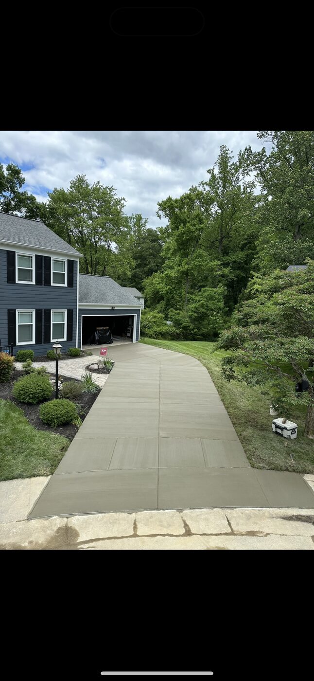 Curved concrete driveway with landscaping at a two-story home