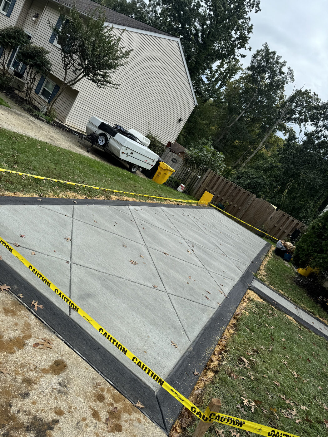 Fresh concrete driveway pour beside a wooden fence