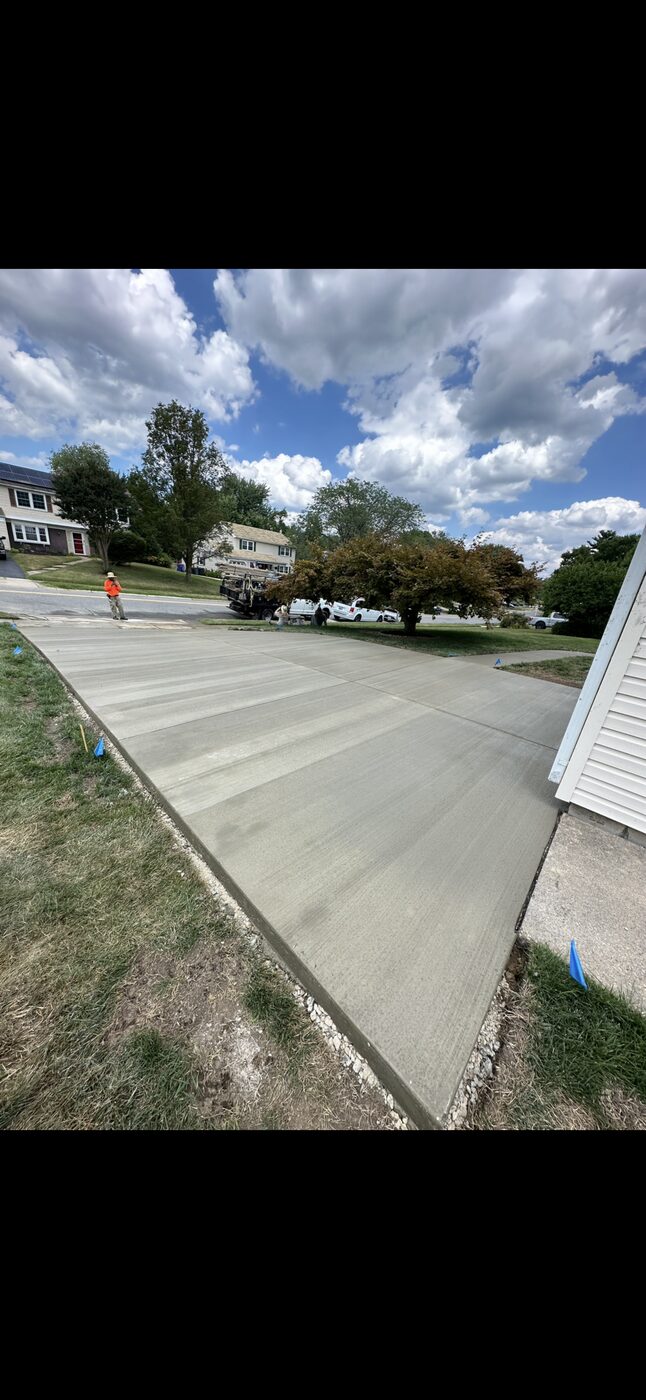 Wide concrete driveway pour with survey flags marking the site