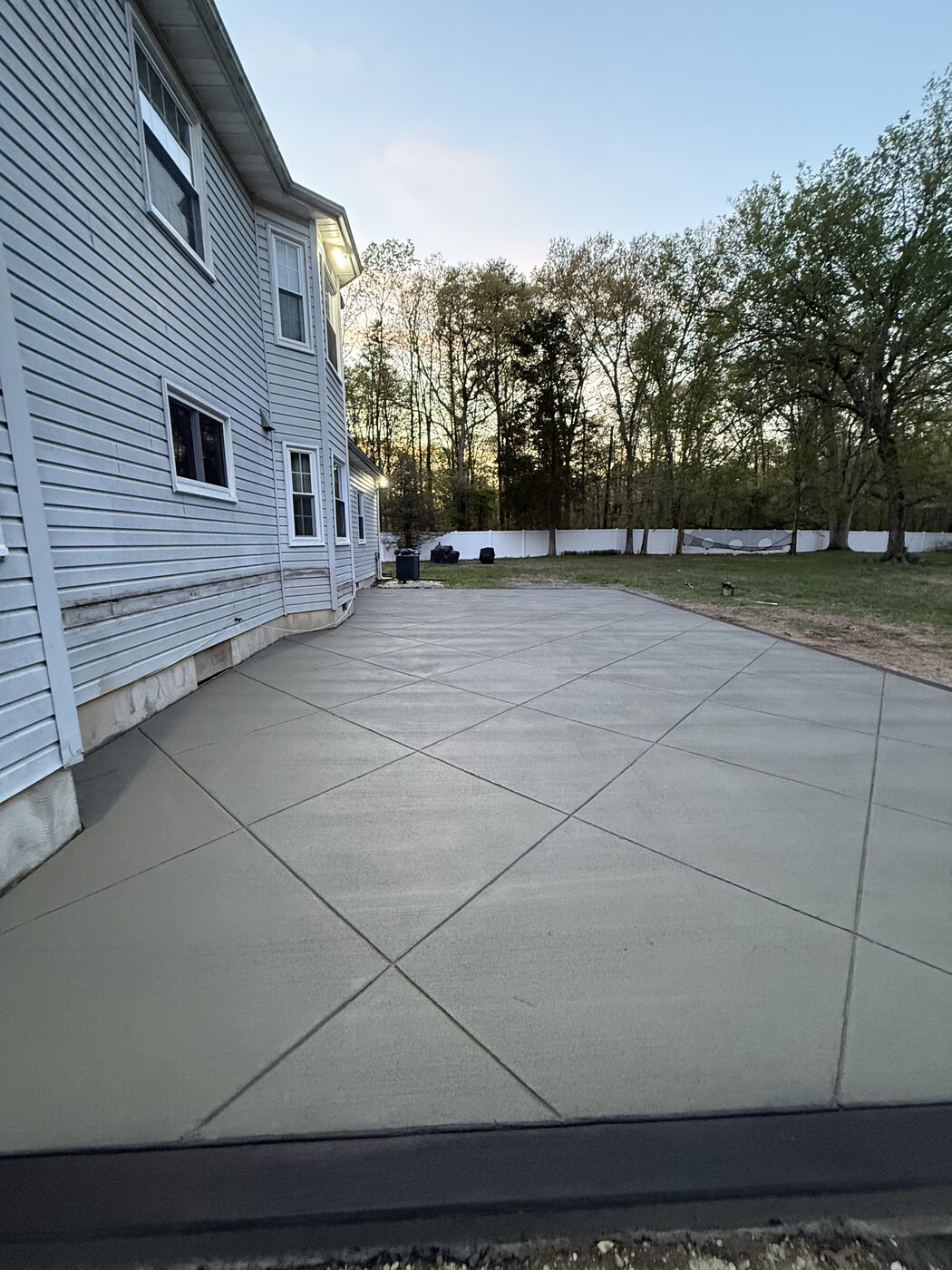 Large concrete patio behind a home at dusk