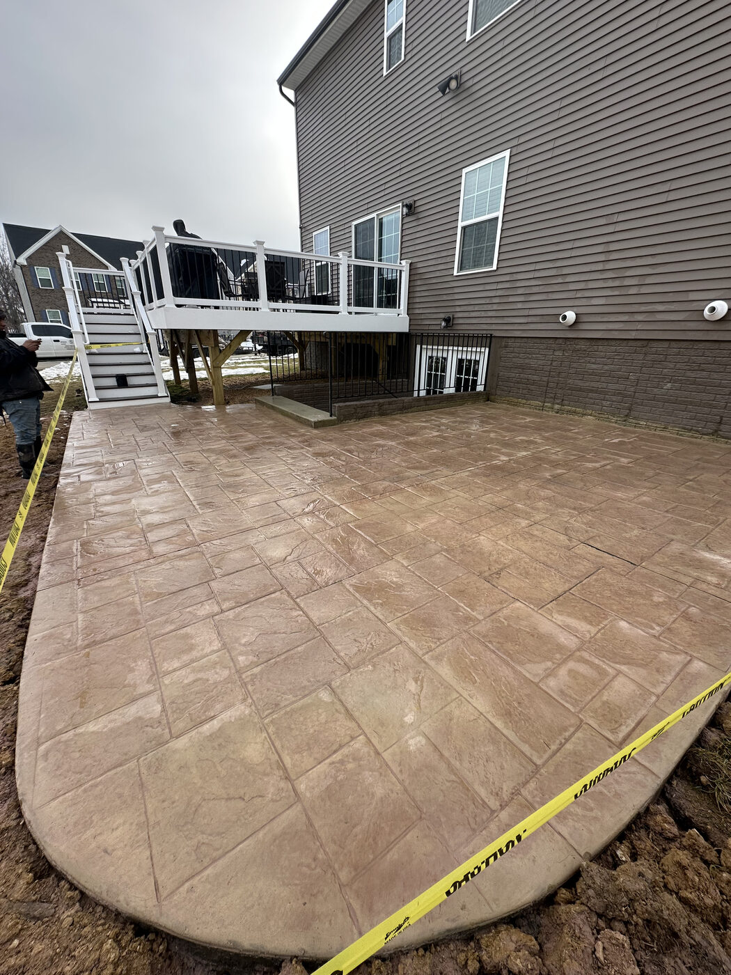 Tan stamped tile-pattern concrete patio with a deck