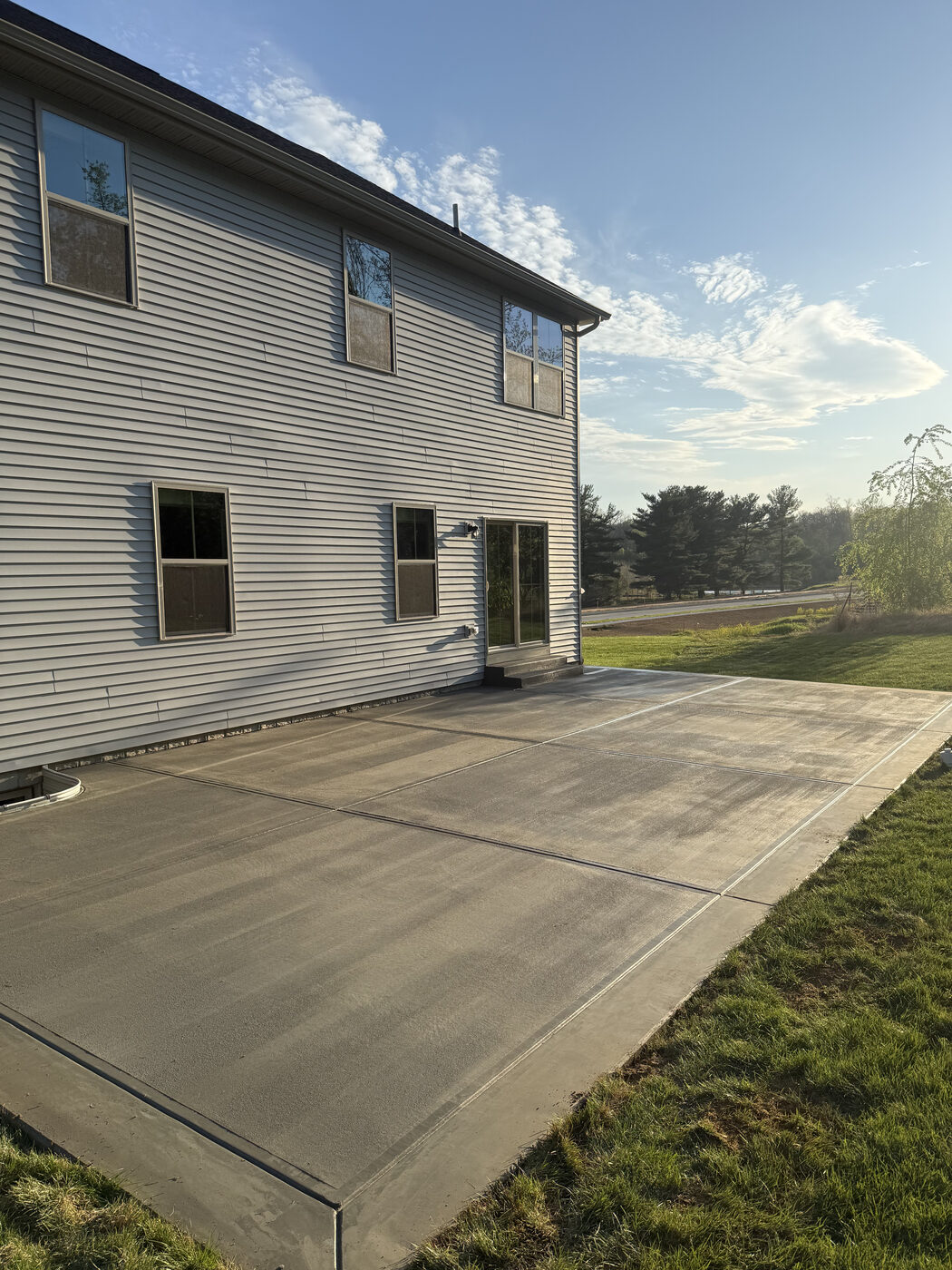 Finished concrete patio slab behind a two-story home