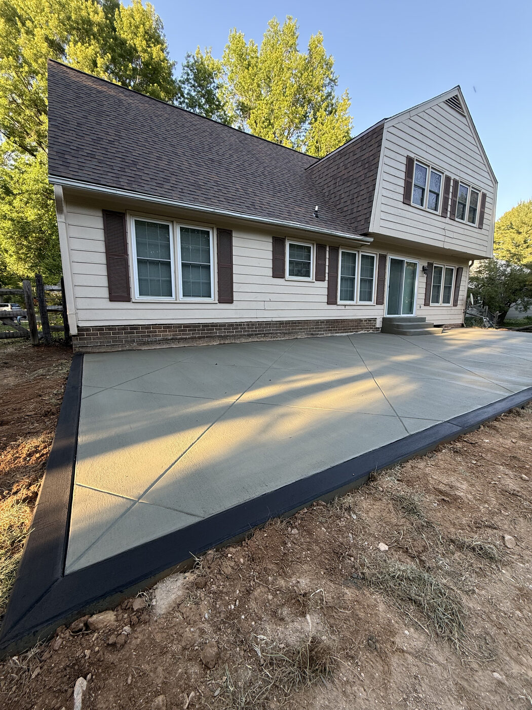 Newly poured concrete driveway and patio combination behind a home