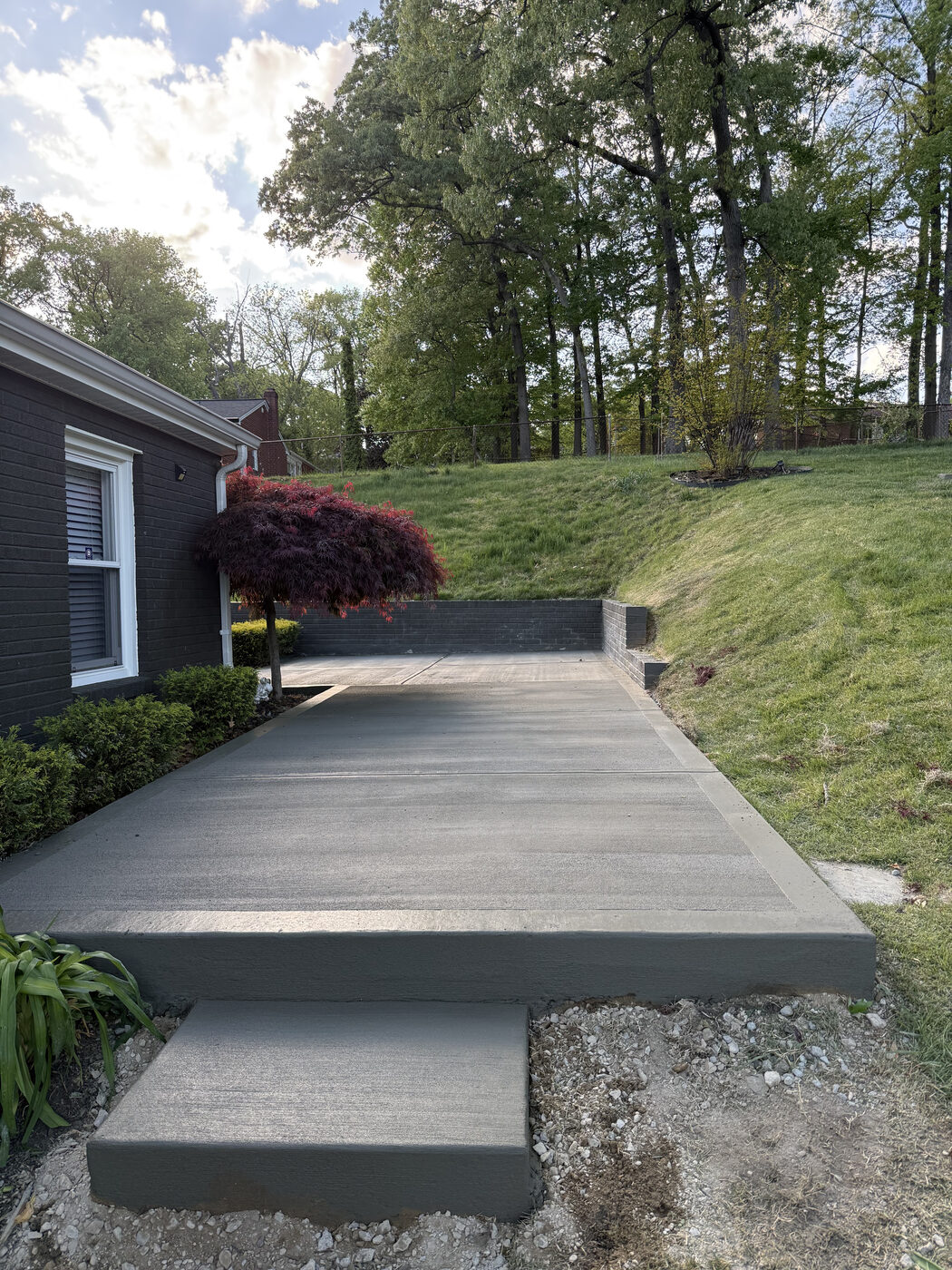 Concrete driveway with integrated step and surrounding landscaping