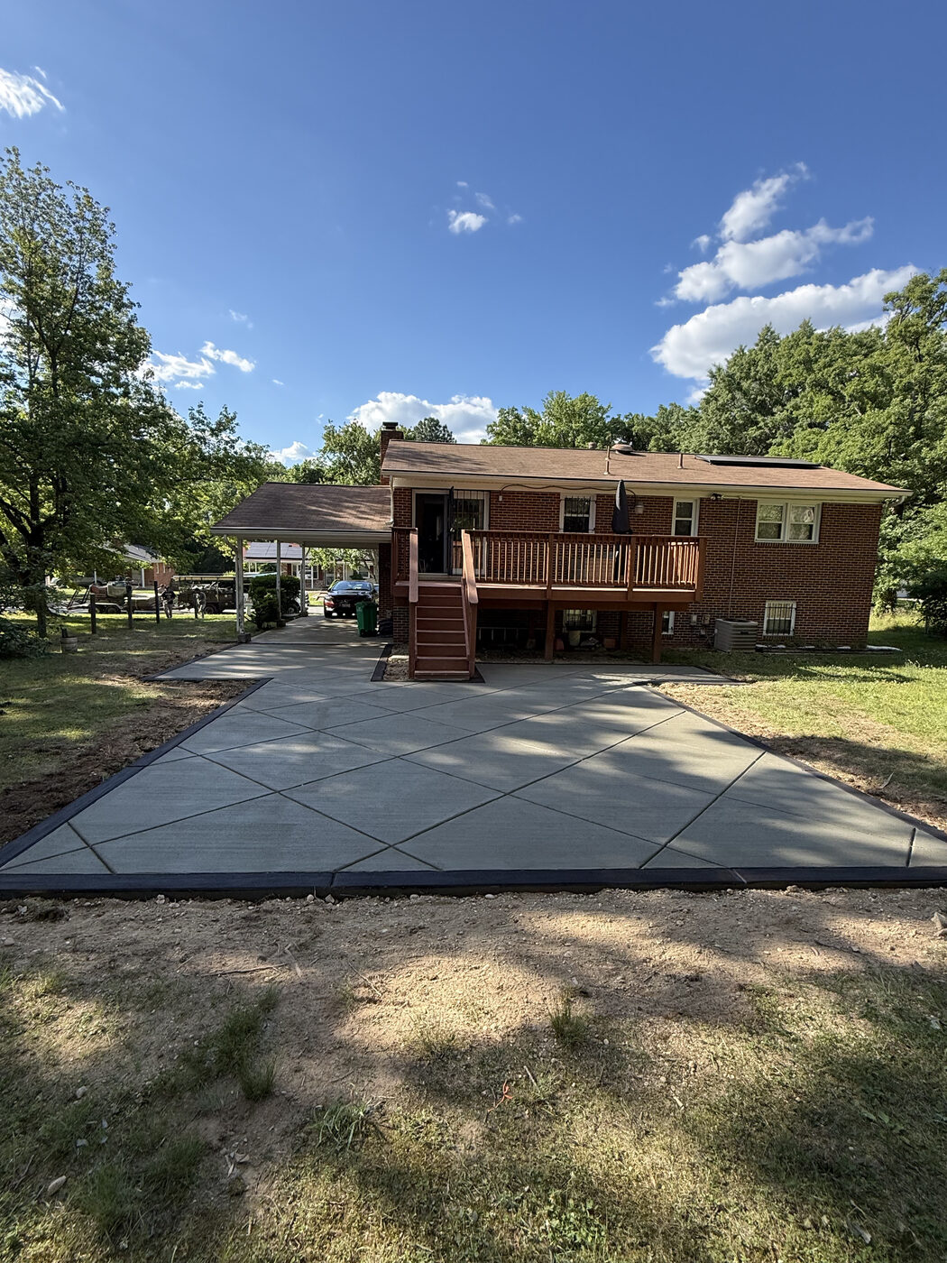Large finished concrete driveway poured behind a brick home
